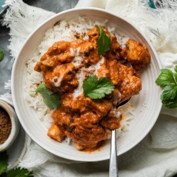 A bowl of butter chicken curry served over rice.