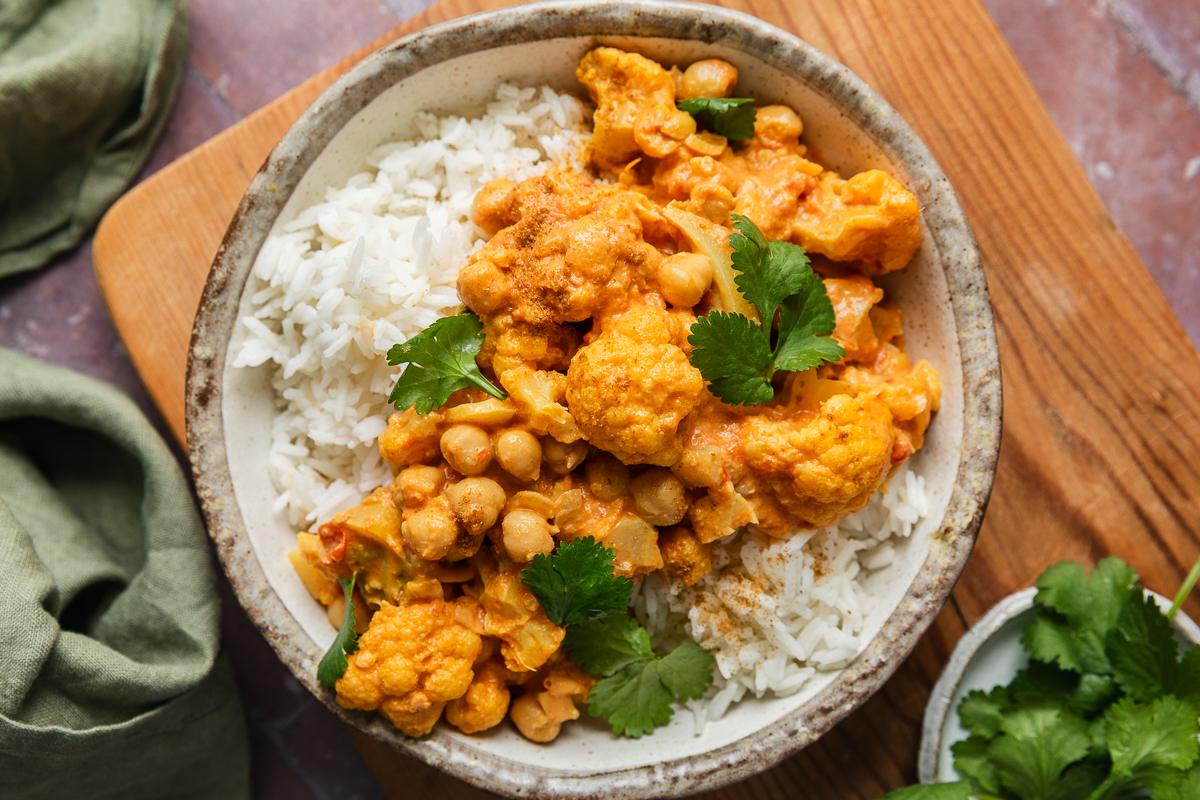 A bowl of creamy vegan cauliflower and chickpea curry served on rice.