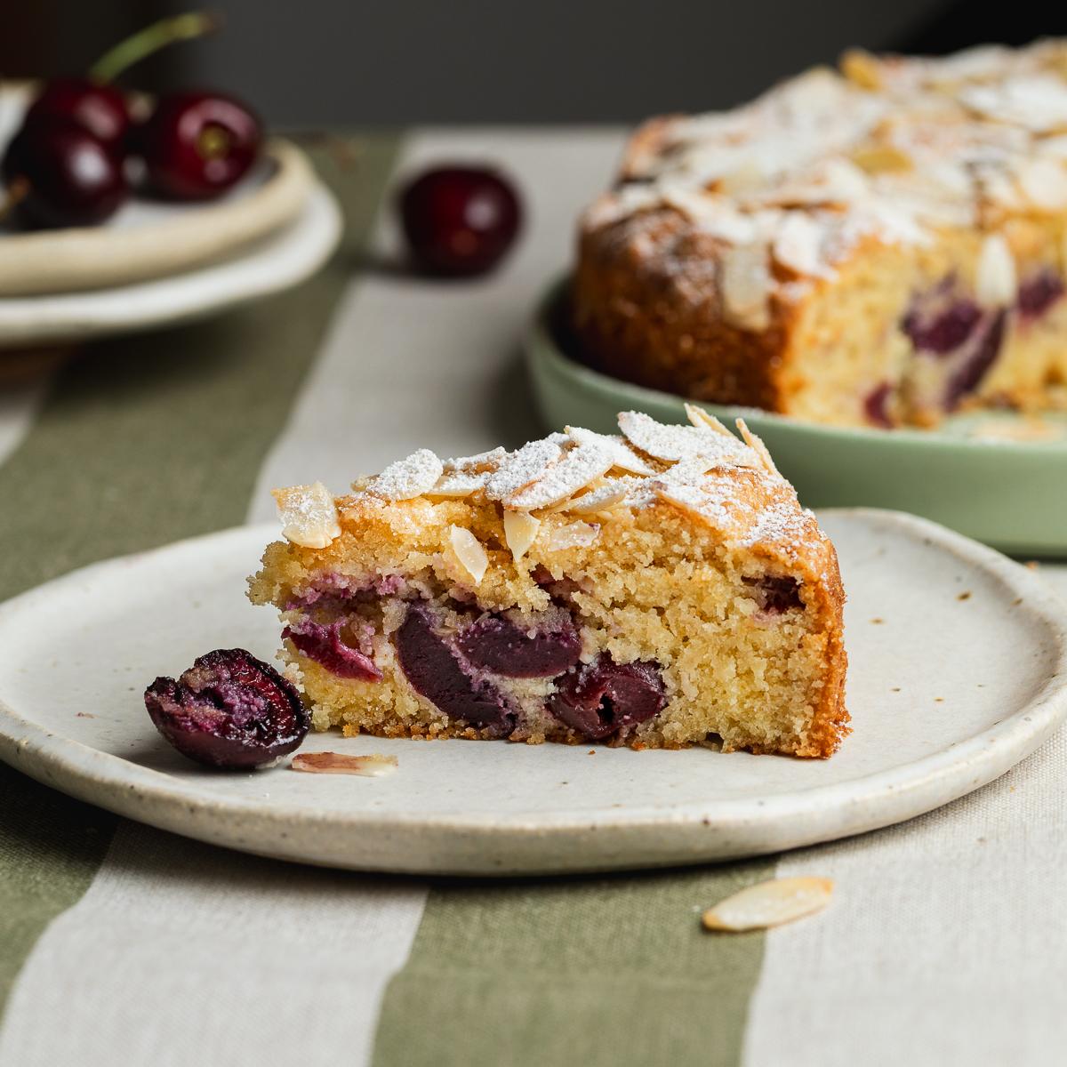 Side view of a slice of cherry almond cake on a plate.