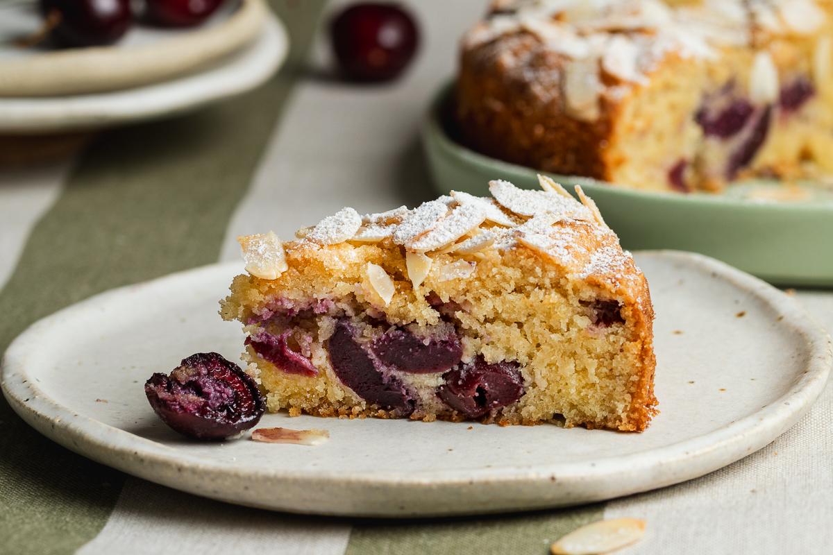 Side view of a slice of cherry almond cake on a plate.