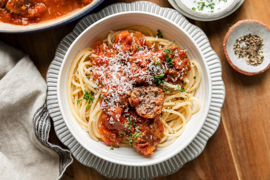 A bowl of gluten-free meatballs served on spaghetti.