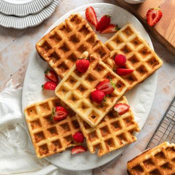 Five gluten-free waffles on a white serving plate.