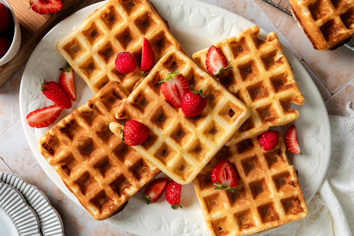 A white oval platter topped with five waffles, ready to serve.
