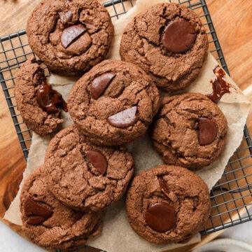 A batch of gluten-free chocolate chip cookies on a wire cooling rack.