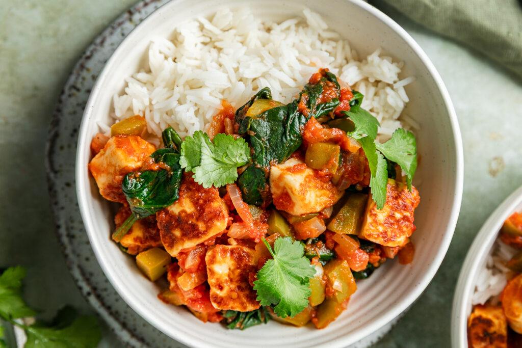 Close up of a bowl of halloumi curry served with rice.