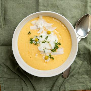 A bowl of mango smoothie with a spoon to the right hand side.
