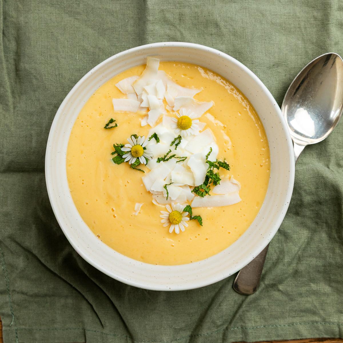 A bowl of mango smoothie with a spoon to the right hand side.