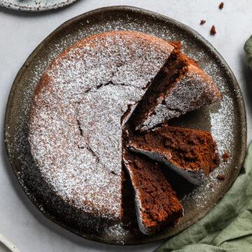 The flourless chocolate cake on a plate with three pieces cut and placed on their sides to show the texture.