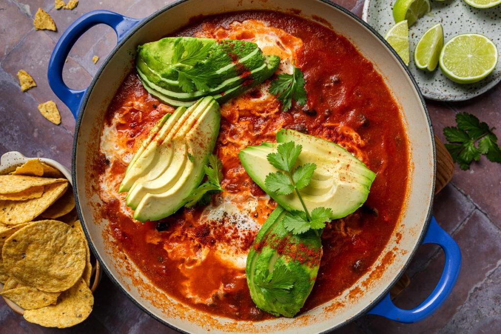 A pan of baked eggs topped with sliced avocado.