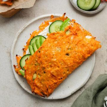 A carrot wrap on a plate filled with cream cheese and cucumber.