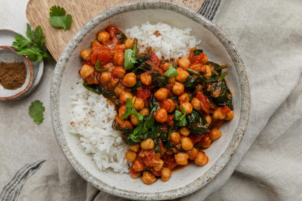 A bowl of gluten-free spinach and chickpea curry served over rice.