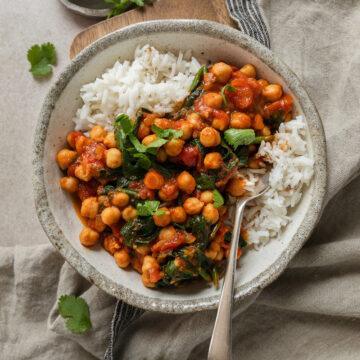 A bowl of gluten-free chickpea and spinach curry served over rice.