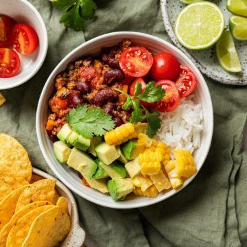 A dairy-free chilli bowl topped with avocado, sweetcorn and tomato.