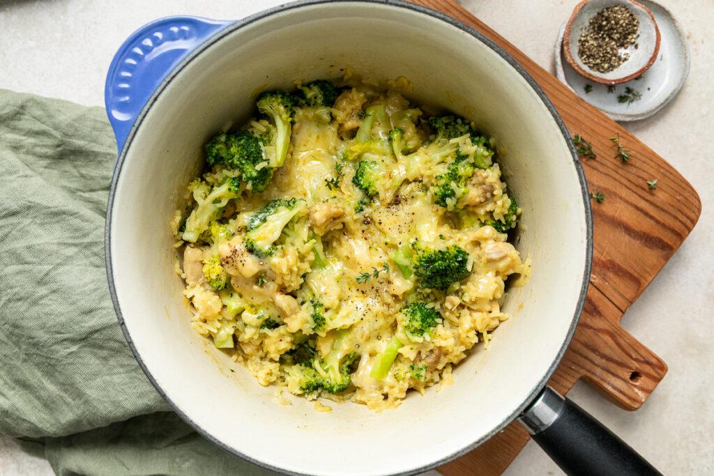 Broccoli and rice casserole in a blue pan, topped with melted cheese.