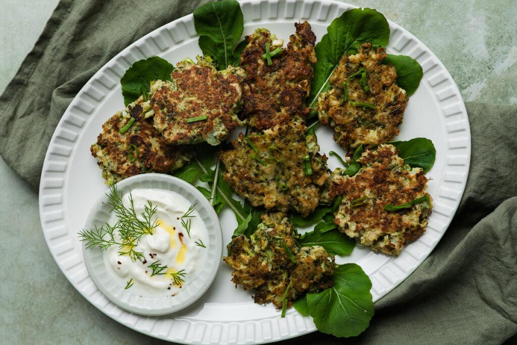 A plate of broccoli fritters served with yogurt and fresh dill.