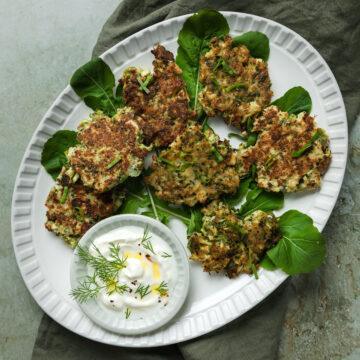 A plate of gluten-free broccoli fritters served with yogurt.