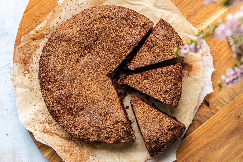 Overhead view of the chocolate cake dusted with cocoa powder, with two slices taken out.