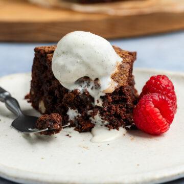 A slice of the gluten-free chocolate cake served with ice cream and raspberries.