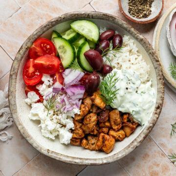 A Greek chicken bowl with rice, topped with fresh dill.