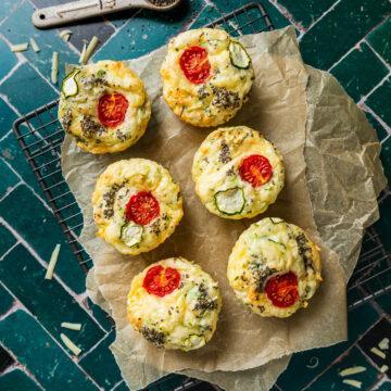 Six gluten-free zucchini slice muffins on a metal cooling rack.