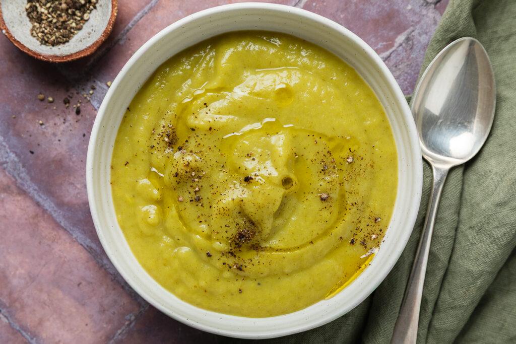 A bowl of homemade gluten-free leek and potato soup sprinkled with black pepper.